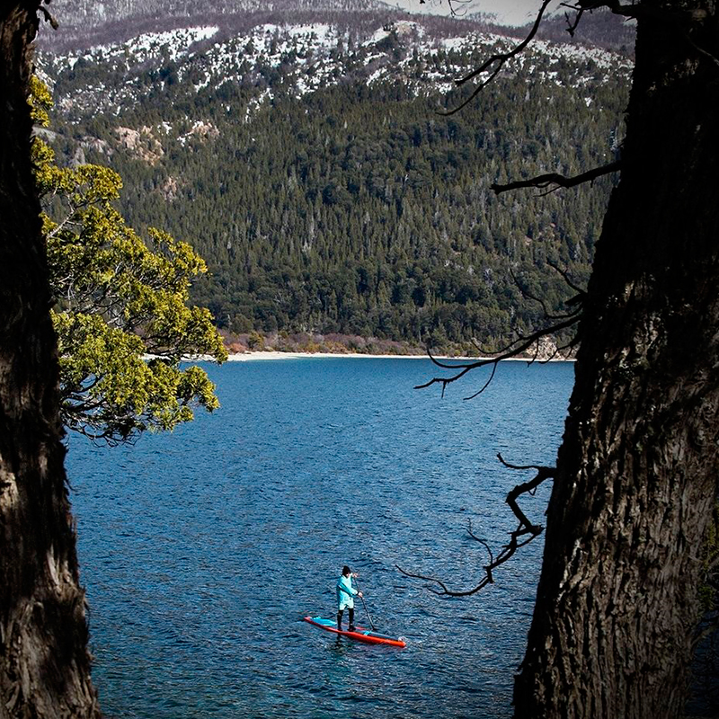 Cristian Almonacid remando en un lago entre bosques.