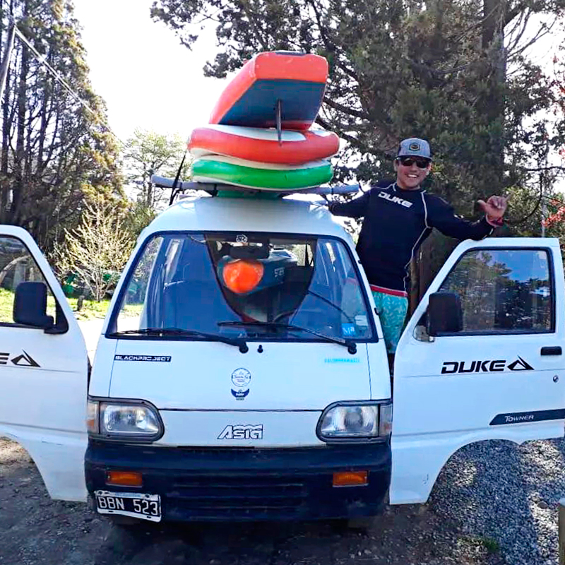 Cristian Almonacid junto a su camioneta y tablas de SUP.